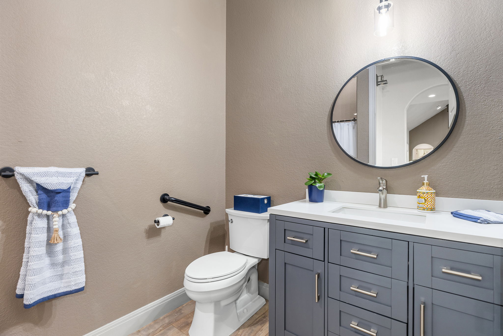 128 Strada Luca Florence, TX 76527 - Photo 27 of 40 Contemporary bathroom with shaker-style vanity, white countertop, round black-framed mirror, and modern fixtures.