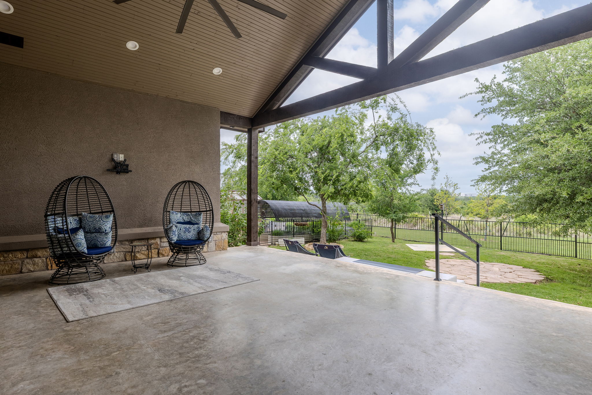 128 Strada Luca Florence, TX 76527 - Photo 32 of 40 Covered outdoor living space featuring a spacious concrete patio and a wood-finish vaulted ceiling with exposed beams, complete with ceiling fan and recessed lighting, offering a comfortable setting to relax while enjoying scenic backyard views.