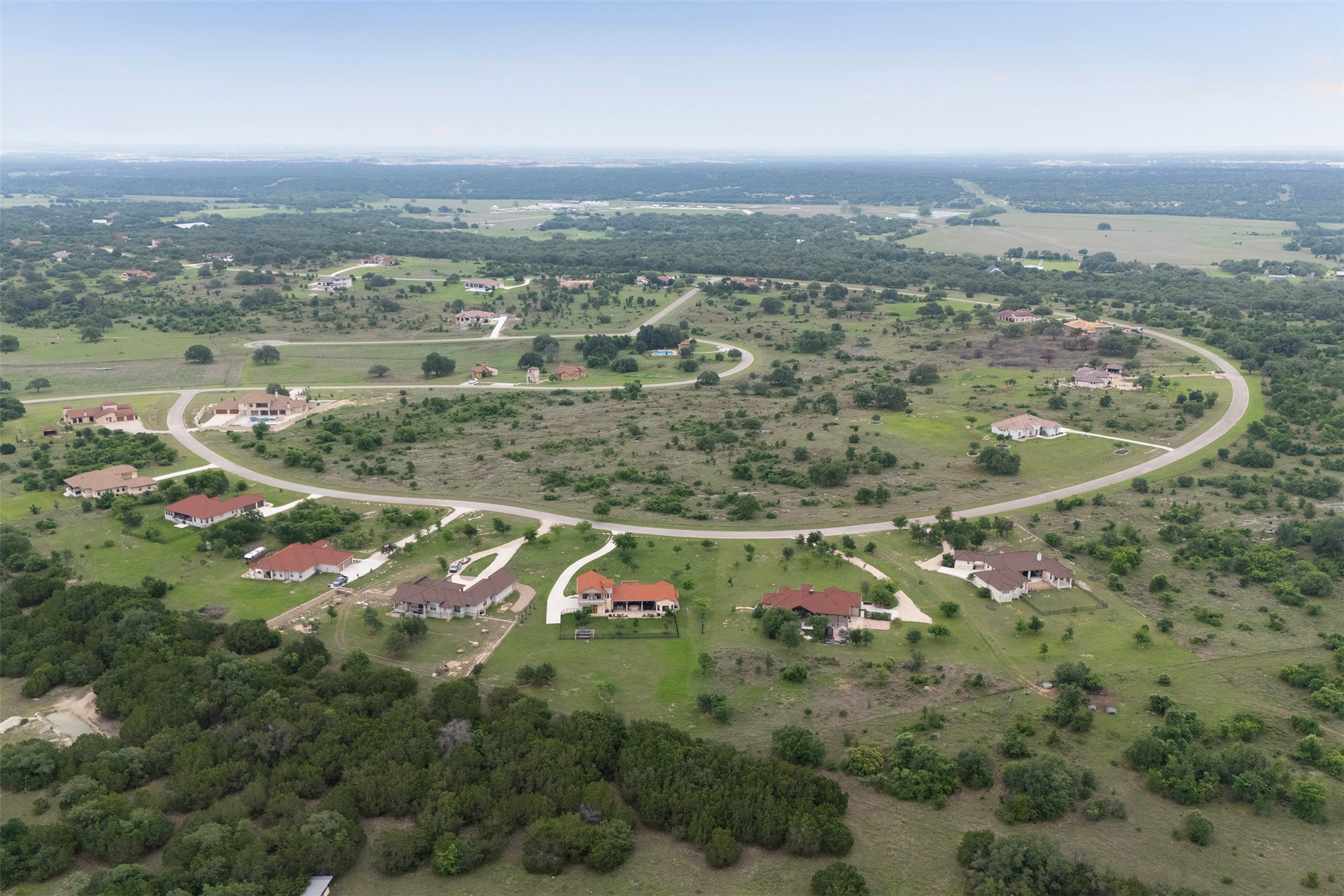 128 Strada Luca Florence, TX 76527 - Photo 37 of 40 Sweeping aerial view of an established residential community featuring paved roads, spacious homesites, and multiple single-family residences, all set within a scenic landscape of rolling terrain and natural greenery.