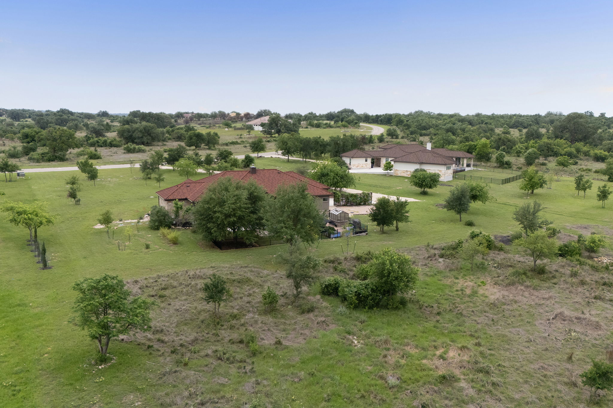 128 Strada Luca Florence, TX 76527 - Photo 38 of 40 Expansive estate setting showcasing two single-story residences with red tile roofs, surrounded by wide open green space, scattered mature trees, and a peaceful, rural landscape that offers both privacy and room to spread out.
