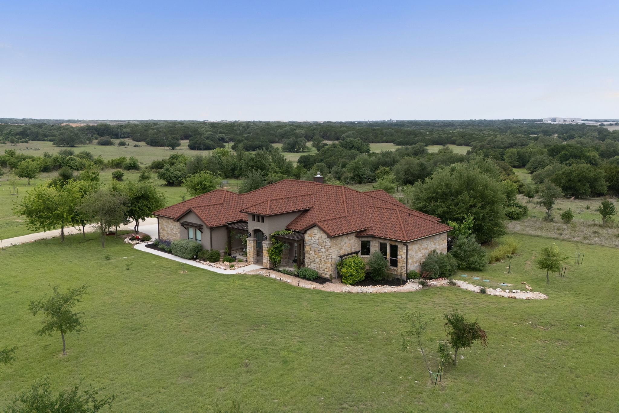 128 Strada Luca Florence, TX 76527 - Photo 39 of 40 Elegant stone and stucco exterior paired with a terra cotta tile roof, highlighted by manicured landscaping, a curved entry walkway, and a spacious homesite that offers privacy and scenic views of the surrounding countryside.