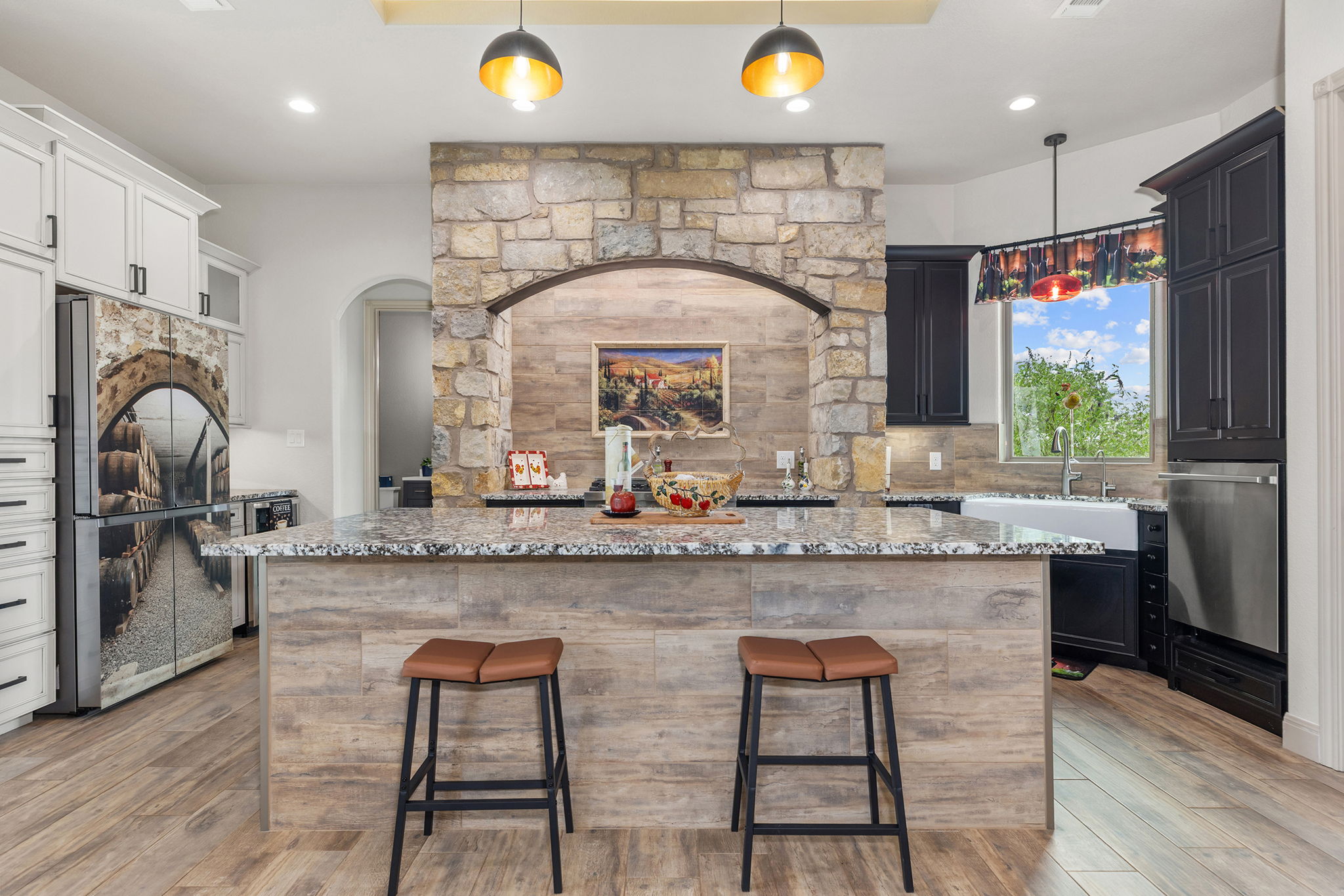 128 Strada Luca Florence, TX 76527 - Photo 7 of 40 Spacious kitchen with large granite island, wood-look paneling, pendant lighting, and stone accent wall for a warm, inviting feel.