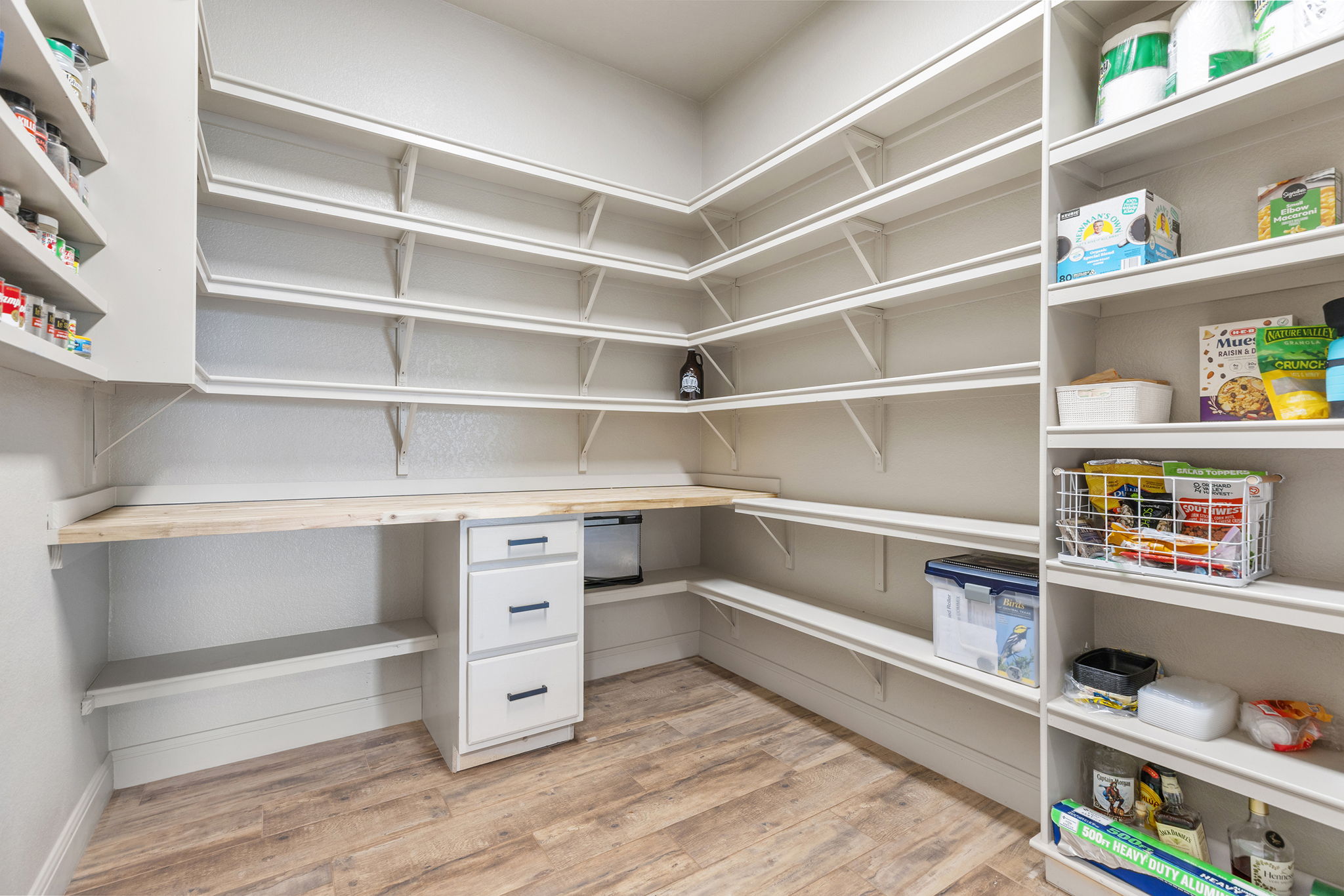 128 Strada Luca Florence, TX 76527 - Photo 10 of 40 Expansive walk-in pantry with extensive built-in shelving, wood countertop workspace, cabinet storage, and wood-look flooring.