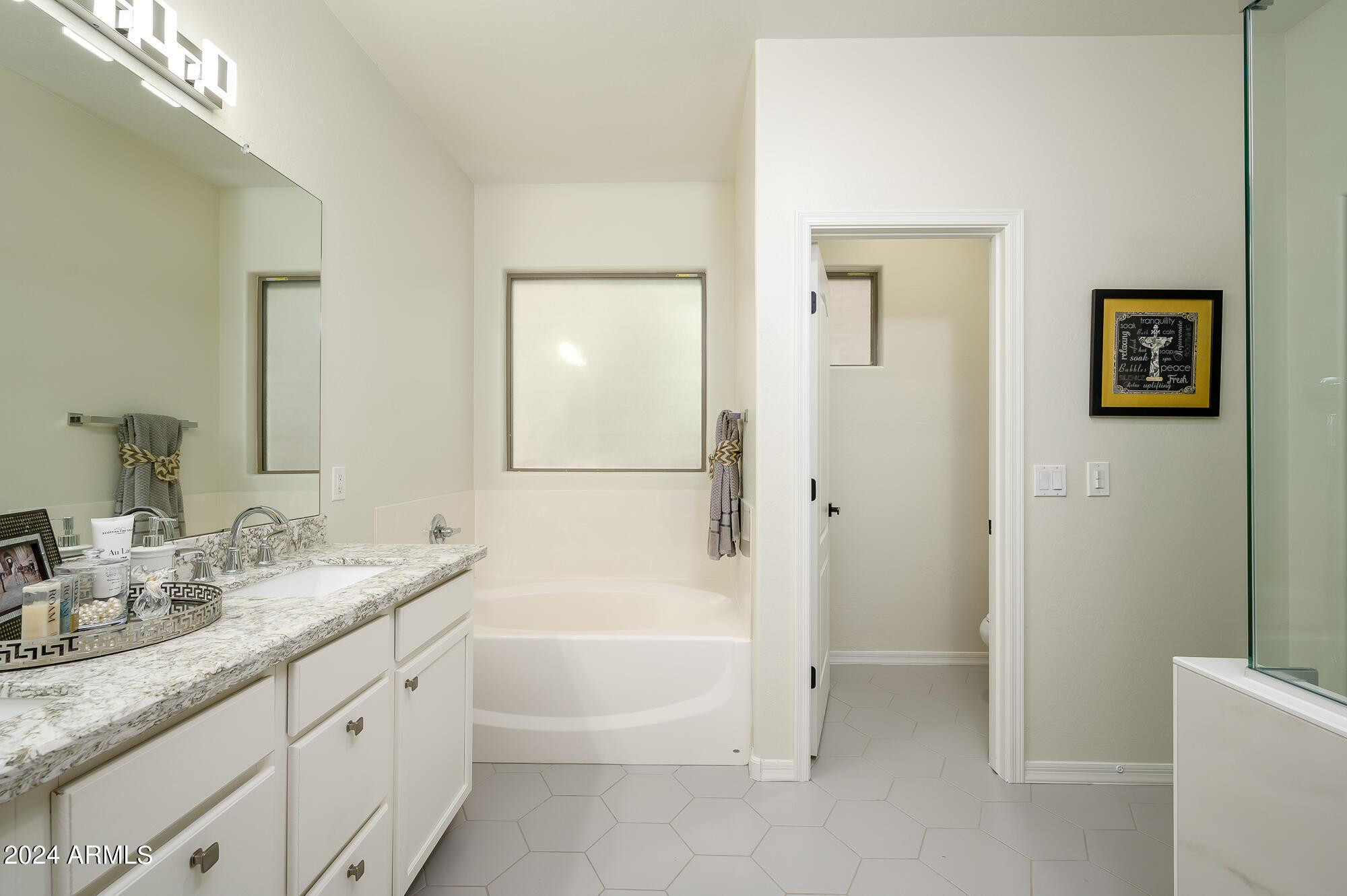 17618 West Crocus Drive Surprise, AZ 85388 - Photo 22 of 34 a bathroom with a granite countertop sink a mirror a bathtub and shower