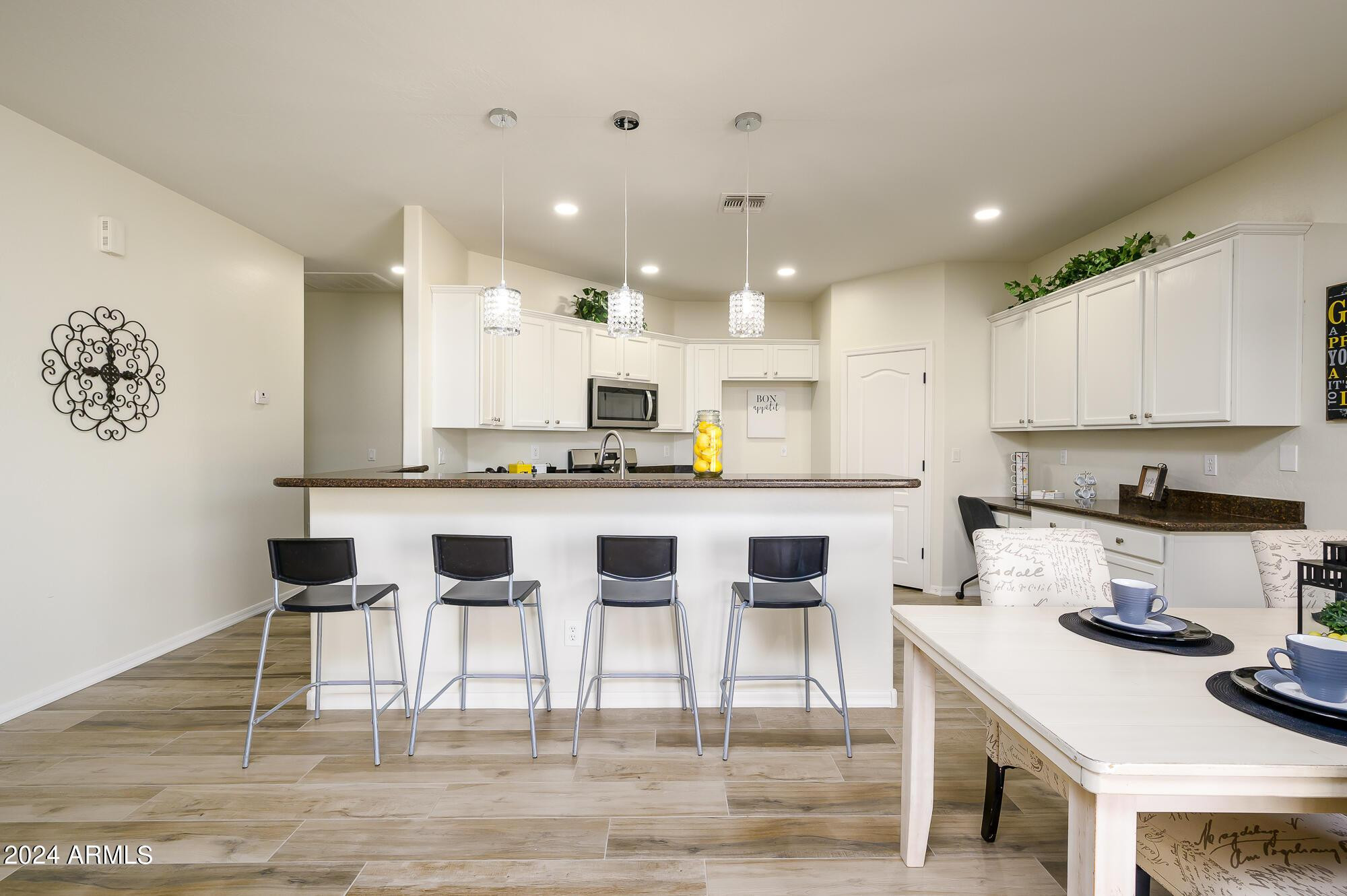 17618 West Crocus Drive Surprise, AZ 85388 - Photo 9 of 34 a kitchen with stainless steel appliances kitchen island granite countertop a stove a sink a refrigerator and white cabinets with wooden floor