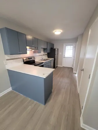 a living room with stainless steel appliances furniture a window and wooden floor