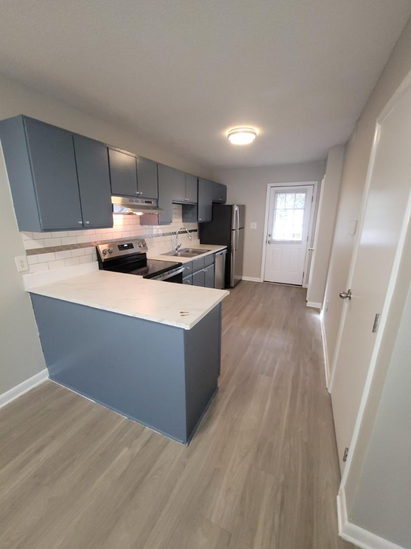 a living room with stainless steel appliances furniture a window and wooden floor