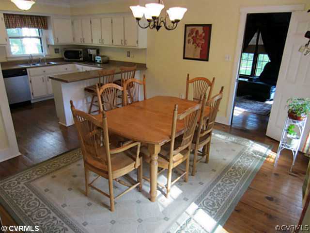 7950 Millvale Road Chesterfield, VA 23832 - Photo 6 of 18 a kitchen with stainless steel appliances granite countertop a stove a sink a microwave a dining table and chairs with wooden floor