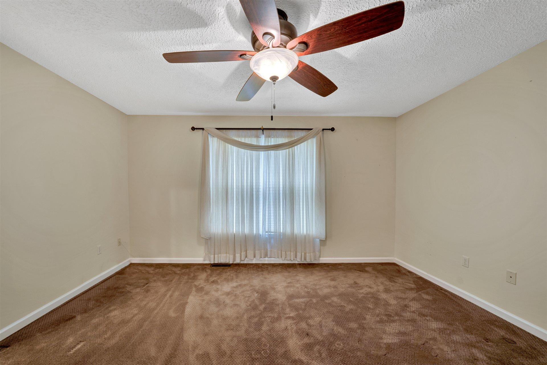 445 Middle Ridge Drive Callaway, VA 24067 - Photo 12 of 25 an empty room with a chandelier fan and windows