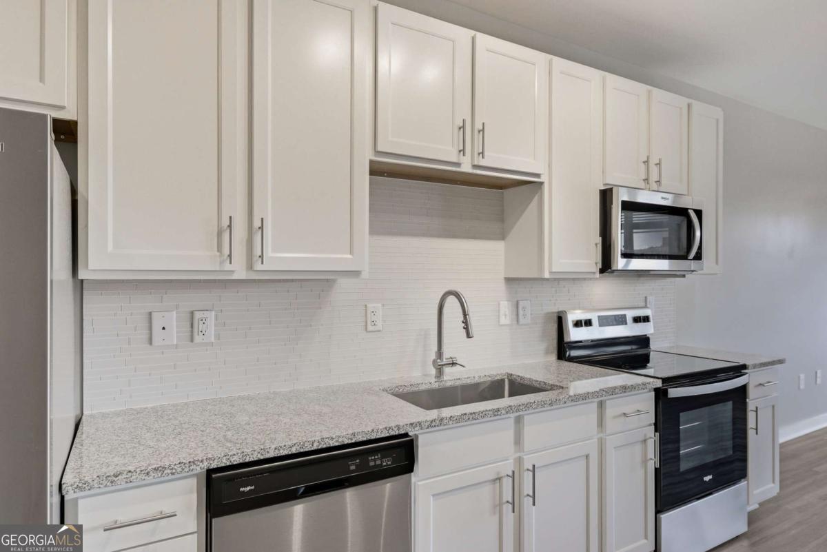 100 Prince Avenue, Unit A407 Athens, GA 30601 - Photo 13 of 27 a kitchen with white cabinets and stainless steel appliances