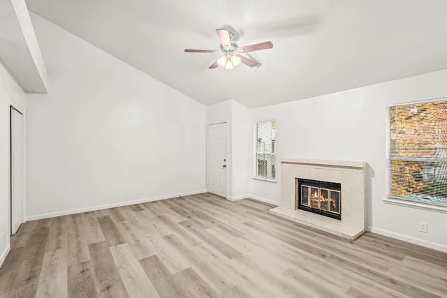 an empty room with windows and fireplace