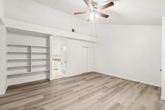 a view of an empty room with a window and wooden floor
