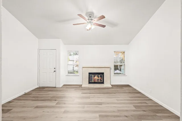 a view of an empty room with a ceiling fan and wooden floor