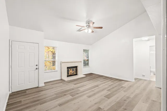a view of empty room with a fireplace and wooden floor
