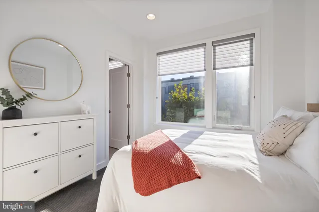 a bedroom with a bed and a large mirror on the dresser