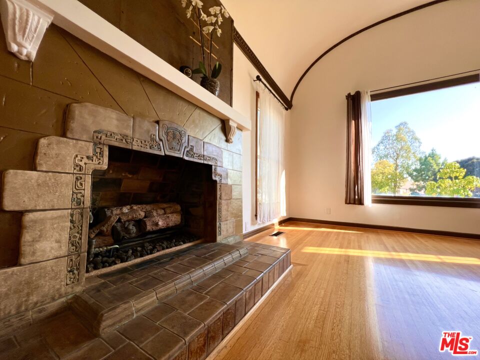 6187 Barrows Drive Los Angeles, CA 90048 - Photo 5 of 35 a view of an empty room with wooden floor fireplace and a window