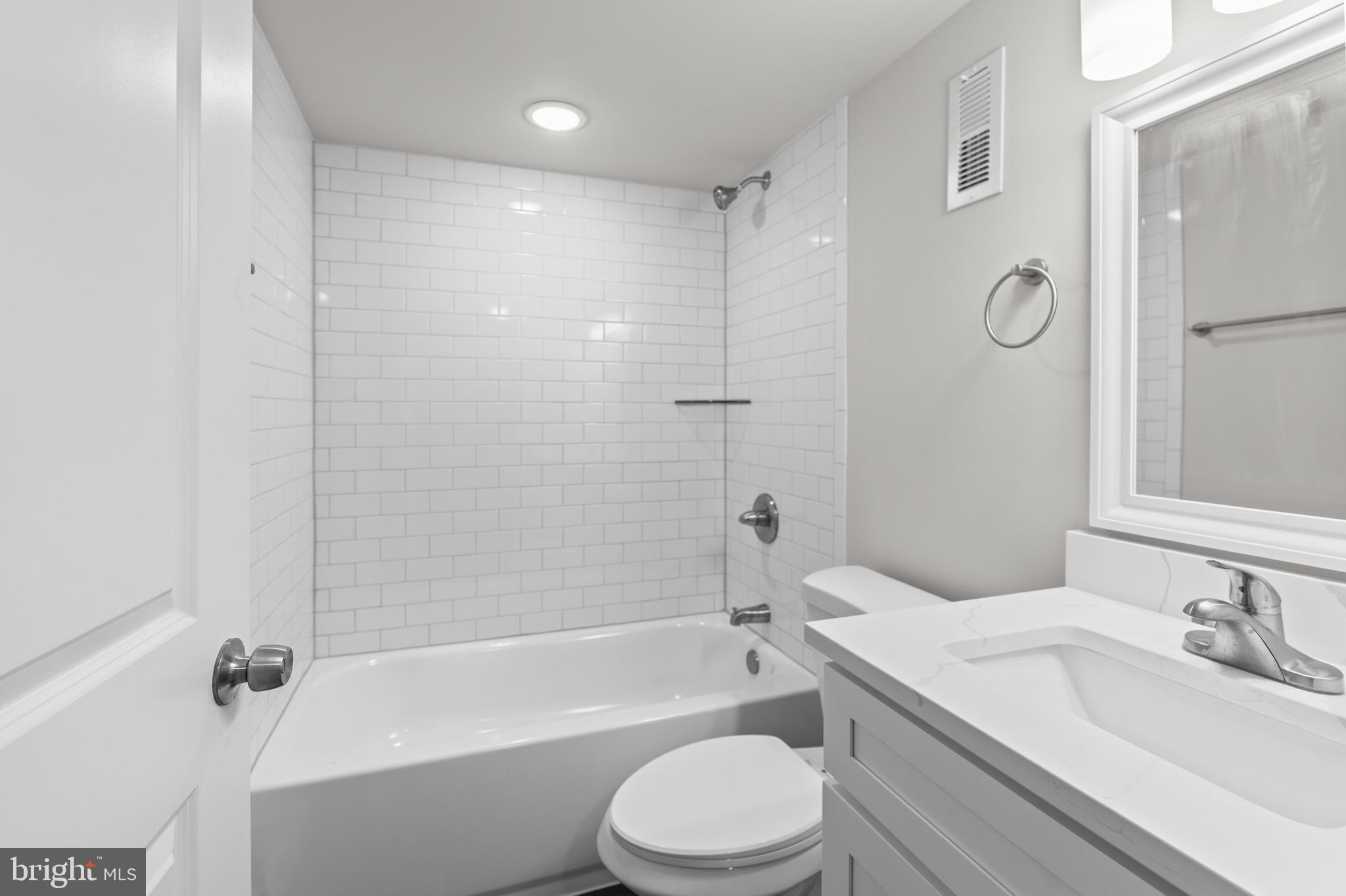 2103 McCulloh Street Baltimore, MD 21217 - Photo 41 of 56 a bathroom with a granite countertop bathtub shower sink vanity mirror and toilet