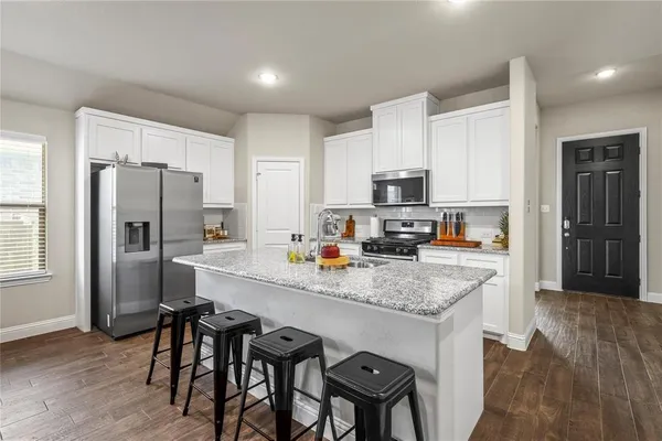 a kitchen with granite countertop a refrigerator and a stove top oven