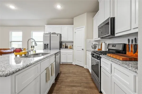 a kitchen with stainless steel appliances granite countertop a stove top oven a sink dishwasher and a refrigerator with the cabinets