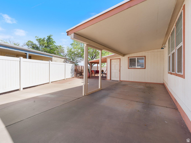 3941 West 40 North Hurricane, UT 84737 - Photo 5 of 55 Expansive carport featuring a concrete surface, covered patio structure, multiple windows, a paneled door, and a white privacy fence