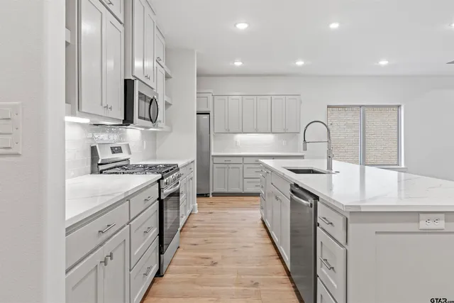 a large kitchen with stainless steel appliances granite countertop a lot of counter space and wooden floor