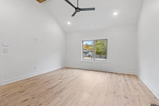 an empty room with wooden floor a ceiling fan and windows