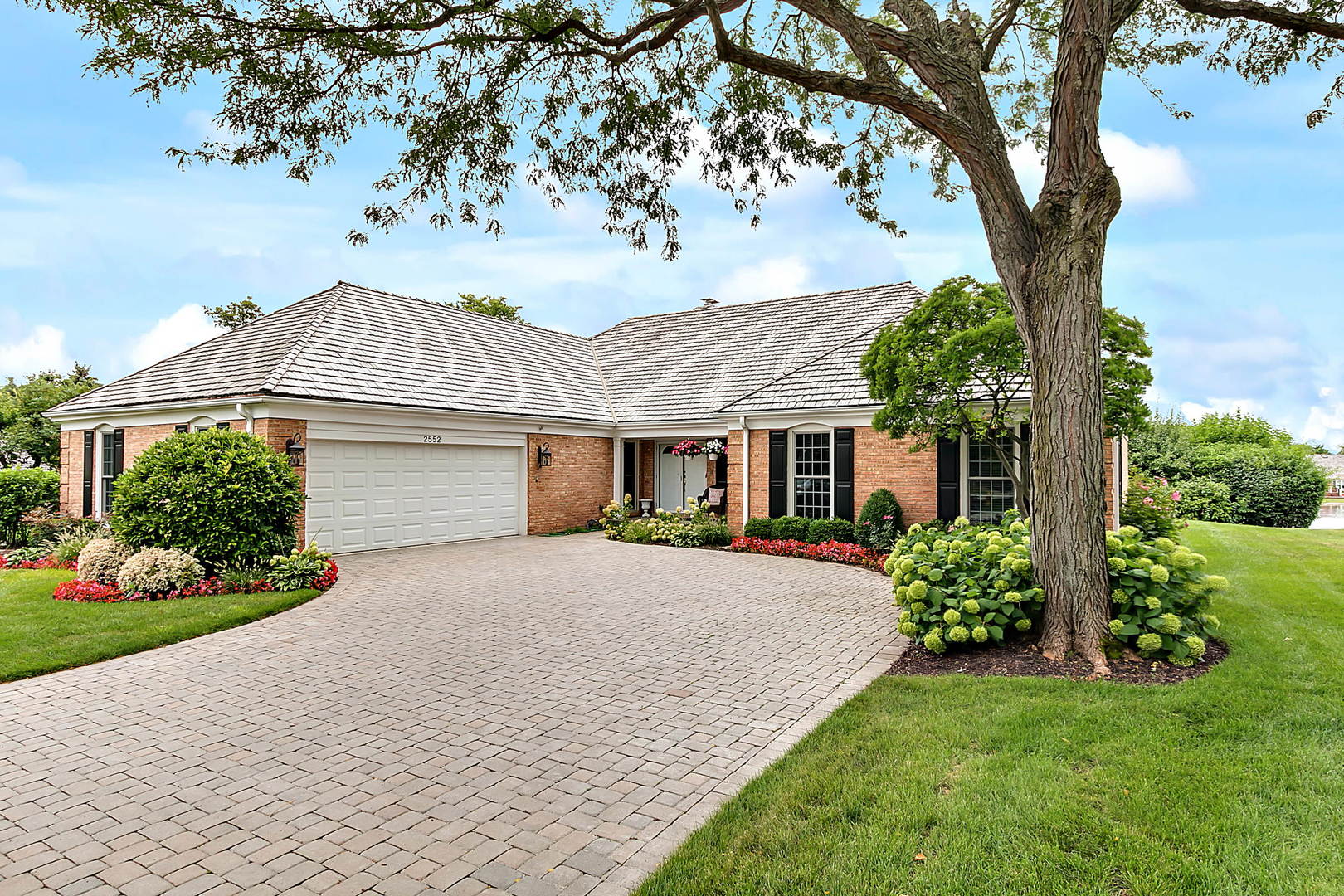 a front view of a house with a garden and trees