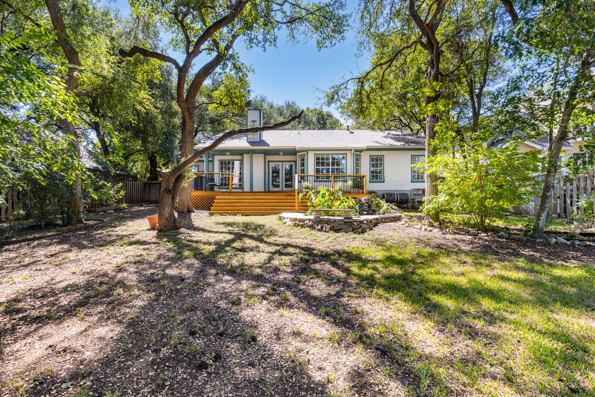 134 Canyon Road Georgetown, TX 78628 - Photo 30 of 40 Mature trees shade a spacious lawn leading to a raised wooden deck.
