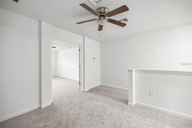 an empty room with a ceiling fan and carpet