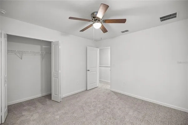 an empty room with closet and a ceiling fan