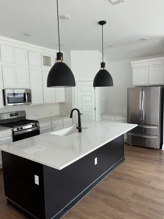 a kitchen with stainless steel appliances granite countertop a sink a stove and a wooden floor