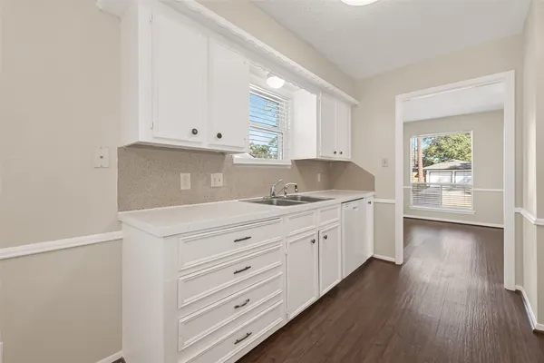 a kitchen with granite countertop white cabinets and wooden floors