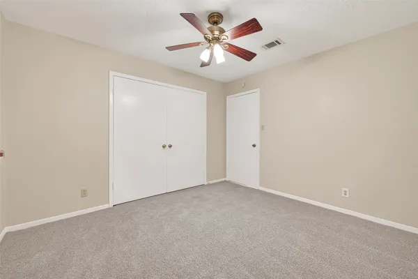 an empty room with closet and a ceiling fan
