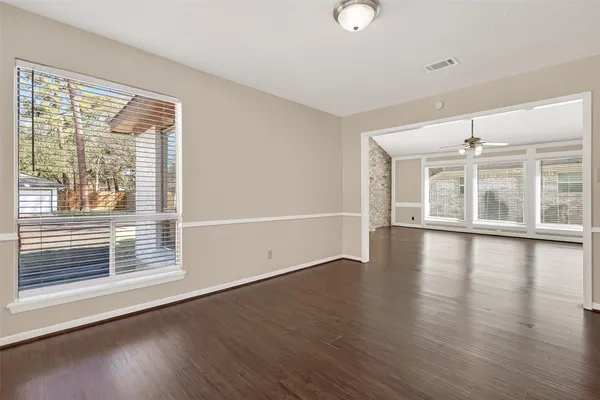 a view of an empty room with wooden floor and a window