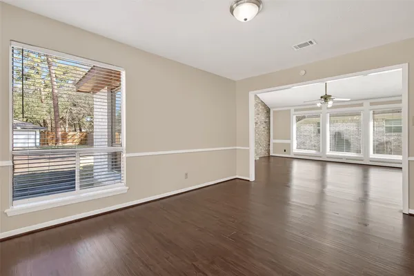 a view of an empty room with wooden floor and a window