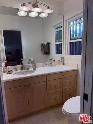 a bathroom with a granite countertop sink a toilet and a mirror