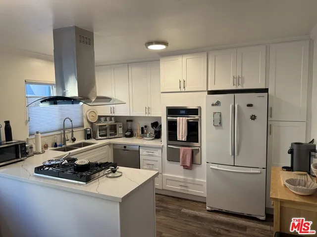a kitchen with refrigerator a stove a sink and white cabinets