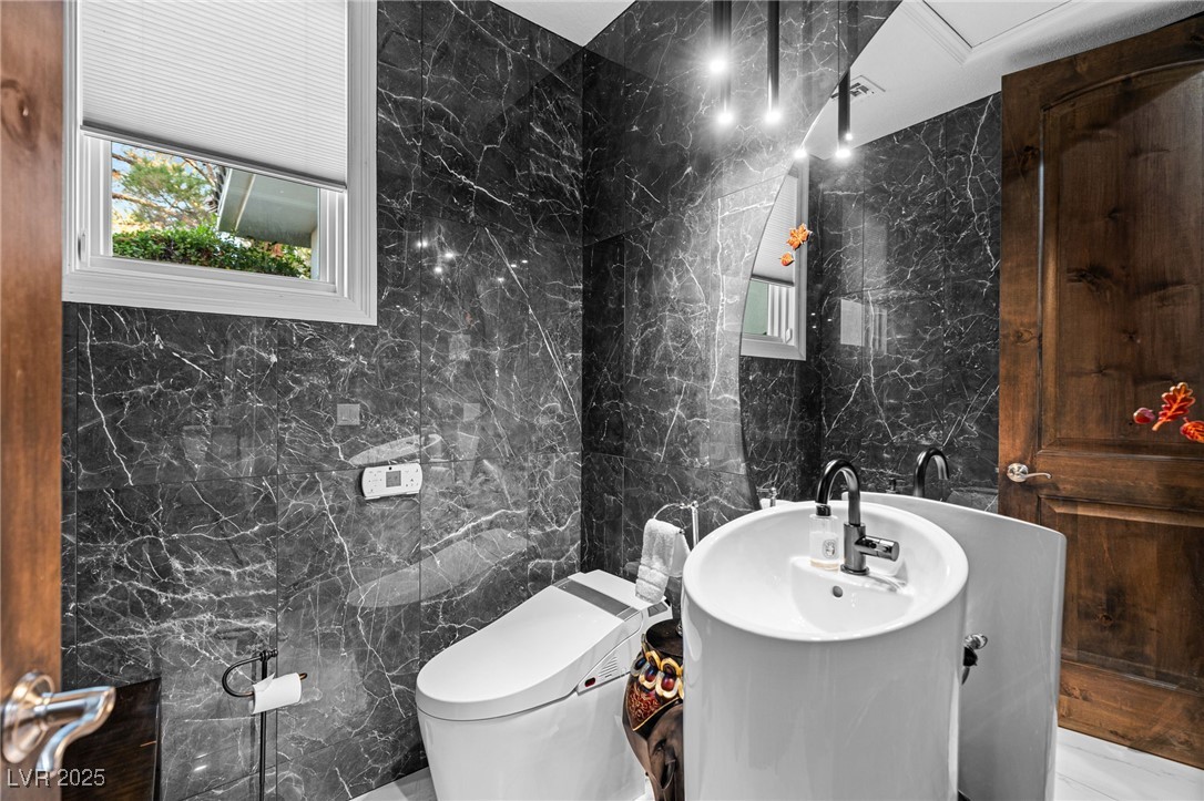 2057 Troon Drive Henderson, NV 89074 - Photo 21 of 41 Half bathroom with tile walls, stone wall, vanity, and marble tiled floors