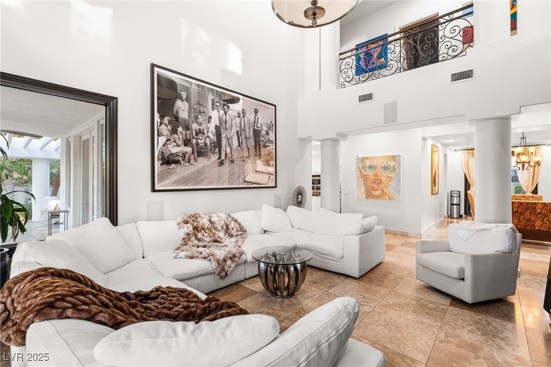 2057 Troon Drive Henderson, NV 89074 - Photo 28 of 41 Living room featuring decorative columns, a towering ceiling, and a chandelier