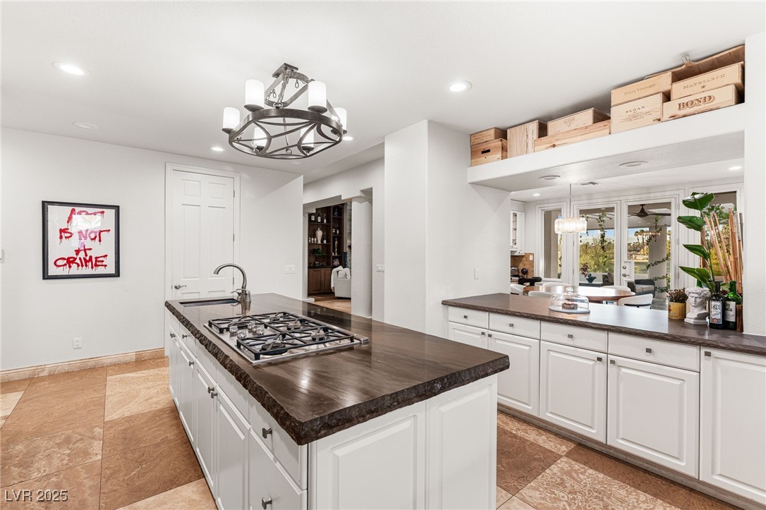 2057 Troon Drive Henderson, NV 89074 - Photo 30 of 41 Kitchen featuring dark countertops, pendant lighting, a chandelier, white cabinetry, and a center island