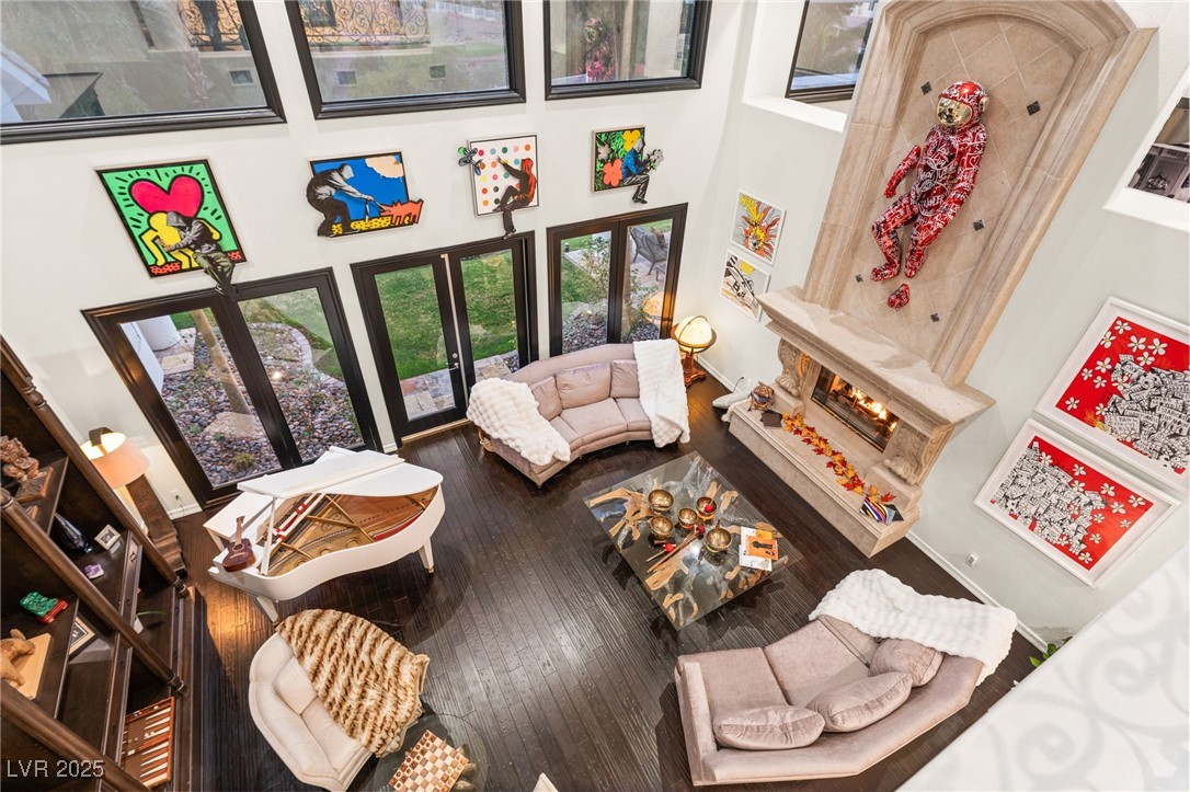 2057 Troon Drive Henderson, NV 89074 - Photo 39 of 41 Living room featuring a towering ceiling, dark wood-style floors, and a warm lit fireplace