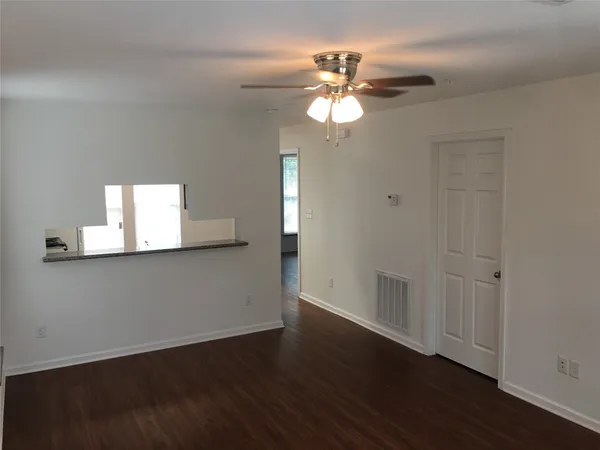 a view of an empty room with wooden floor and a window