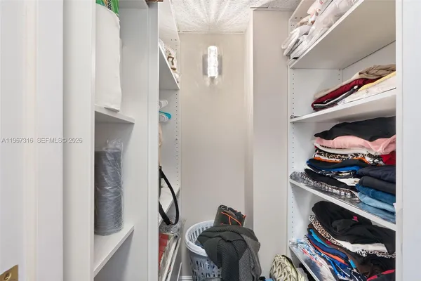 a view of walk in closet with clothes and shoes