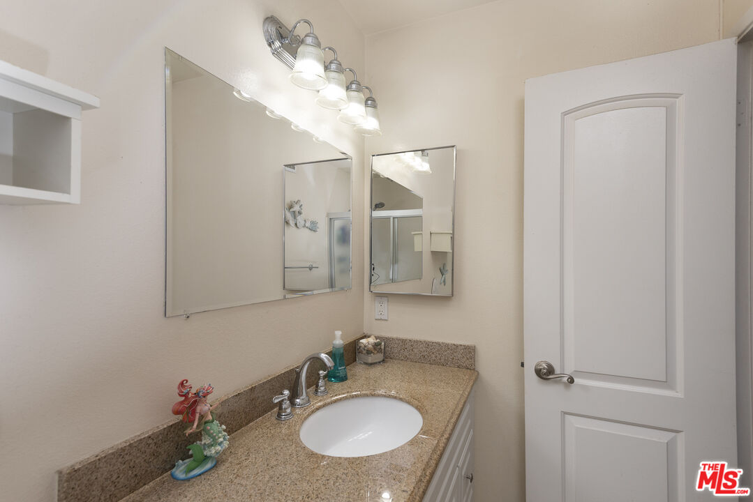 19355 Sherman Way, Unit 37 Reseda, CA 91335 - Photo 8 of 12 a bathroom with a granite countertop sink a mirror and a shower