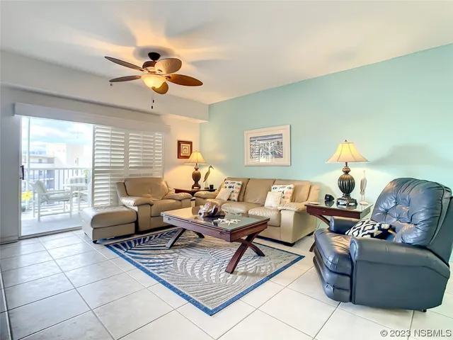 a living room with couch a large window and a chandelier