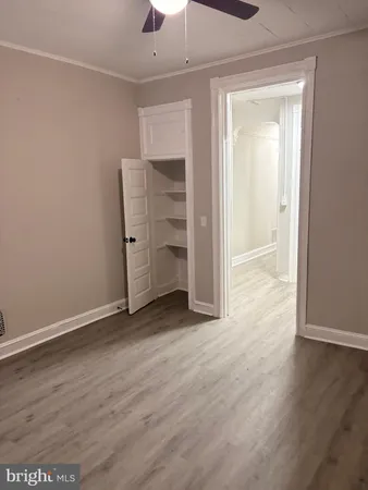 an empty room with wooden floor closet and windows