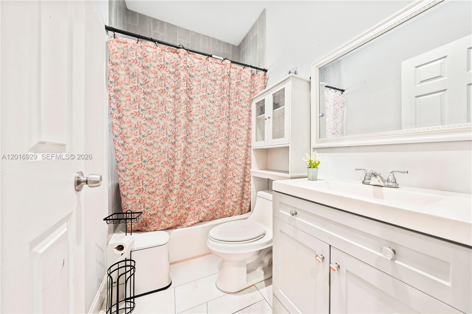 4721 Northwest 15th Court, Unit 1 Miami, FL 33142 - Photo 6 of 11 a bathroom with a granite countertop sink a toilet and a shower curtain