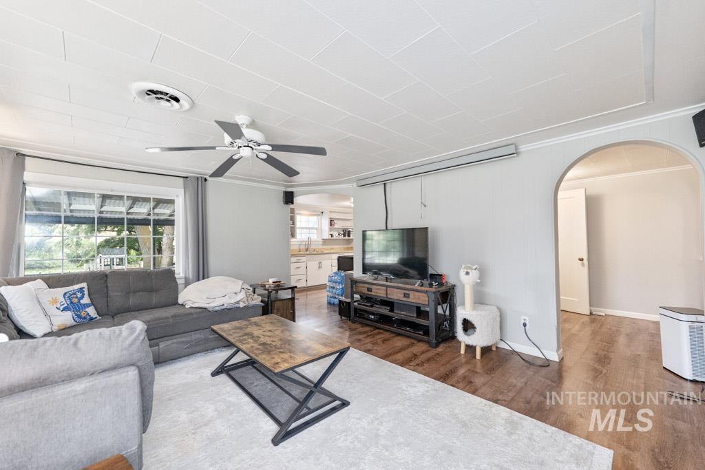 259 Highway 12 Pomeroy, WA 99347 - Photo 19 of 45 Living area featuring a ceiling fan, wood-finish flooring, white ceiling panels, and an arched doorway