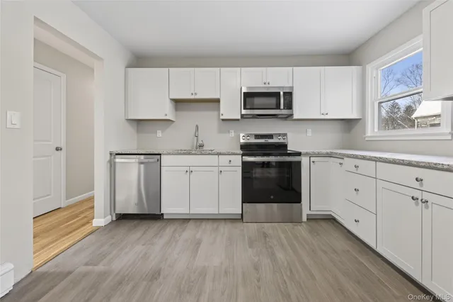 an empty room with wooden floor cabinet and windows
