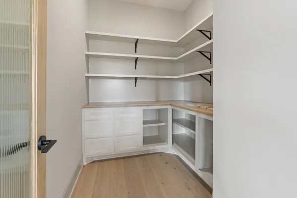a view of an empty room with wooden floor closet and a window
